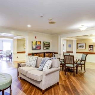 A cozy living room with a sofa, chairs, and artwork on the walls.