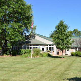 A scenic view of a building surrounded by a well-maintained lawn and trees on a sunny day.