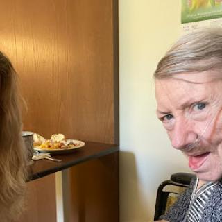 A lighthearted moment captured between two individuals, one playfully adorned with a faux mustache.
