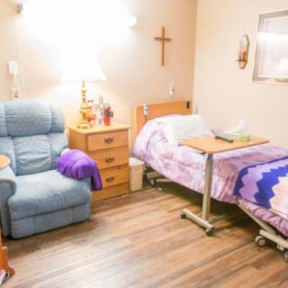 A cozy hospital room with a bed, reclining chair, and bedside table.