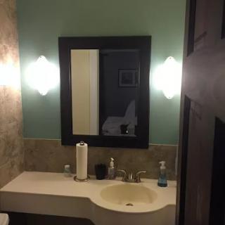 A modern bathroom with a sleek sink, large mirror, and stylish lighting.