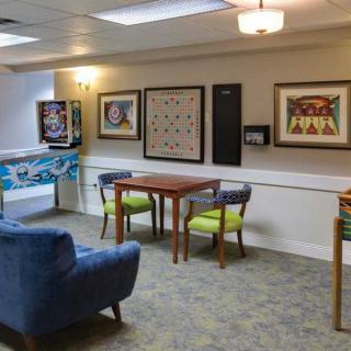 A cozy game room featuring a table and chairs, pinball machine, and wall art.