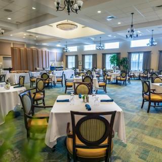 An elegant dining area set with tables and chairs, featuring chandeliers and a formal atmosphere.