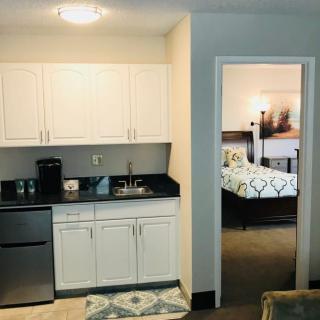 A compact kitchenette with a view into a bedroom in a modern apartment setting.
