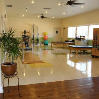 A spacious physical therapy room equipped with various exercise tools and rehabilitation equipment.