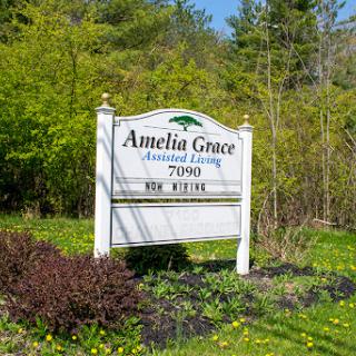 The sign of Amelia Grace Assisted Living surrounded by lush greenery.