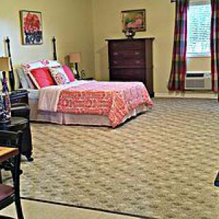 A neatly arranged bedroom with a bed, dresser, and window.