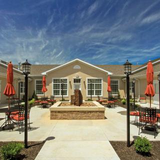 A serene courtyard featuring a central fountain surrounded by outdoor seating and umbrellas.