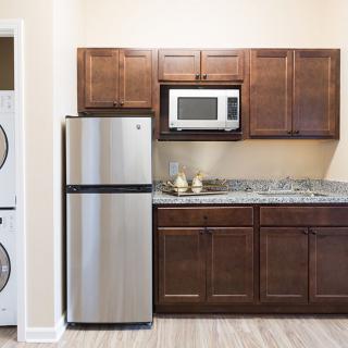 A modern kitchen with wooden cabinets, a stainless steel refrigerator, and a microwave.