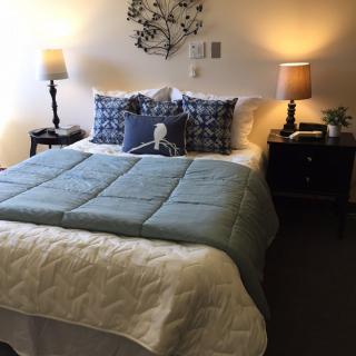 A cozy bedroom with a neatly made bed, flanked by two nightstands and lamps.