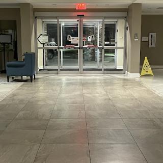 A view of the hotel lobby showcasing the entrance doors, a seating area, and a caution sign on the floor.