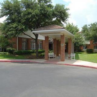 A brick building entrance with surrounding greenery and trees.