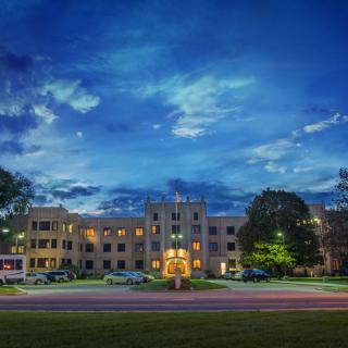 A well-lit building at night with a vibrant sky and parked cars.