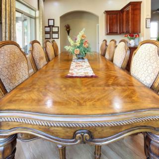 A spacious dining room with a large wooden table and ornate chairs.