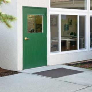 A green door next to large windows on a building exterior.