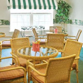 A cozy indoor cafe with rattan furniture and a striped awning, bathed in natural light.