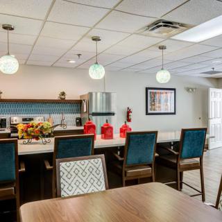 A modern kitchen and dining area with pendant lighting and colorful chairs.