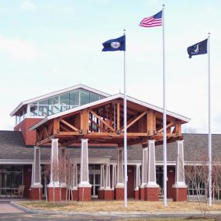 The entrance of a modern building featuring multiple flagpoles with flags.