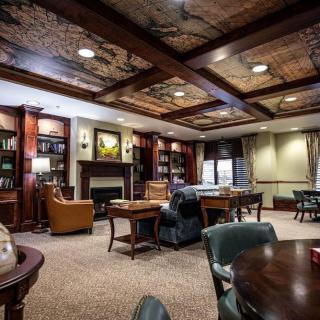A cozy library interior with wooden bookshelves, a fireplace, and comfortable seating.
