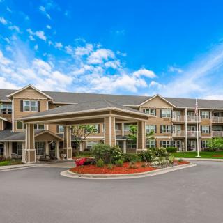 A spacious residential building with landscaped surroundings under a partly cloudy sky.