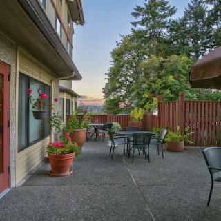 A cozy outdoor patio with tables, chairs, and potted plants surrounded by a wooden fence in the evening.
