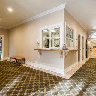 A brightly lit hallway with a reception area and carpeted floors.