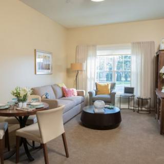 Cozy living room with a sofa, coffee table, and dining area by a large window.