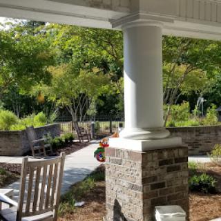 A serene outdoor space featuring a columned porch and beautifully landscaped garden.