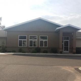 A small commercial office building with large windows and a single door entrance.