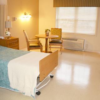 A well-lit hospital room with a bed and seating area.