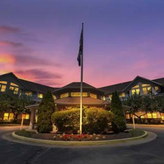 A hotel's grand entrance at sunset with a flagpole in the center.
