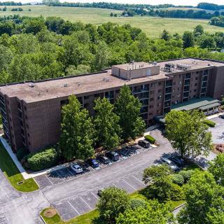 Aerial view of a residential apartment building surrounded by trees and fields.