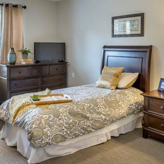 A cozy bedroom with a single bed, dresser, and television.