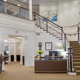 A spacious lobby area featuring a reception desk and a grand staircase.