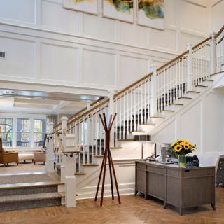 A spacious and elegantly designed lobby featuring a grand staircase and tasteful decor.