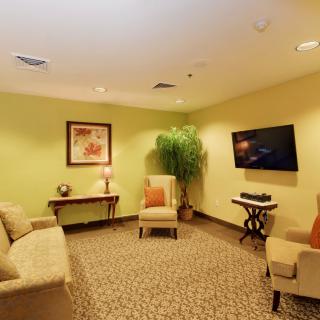 A cozy living room with modern decor, featuring a sofa, chairs, a television, and wall art.