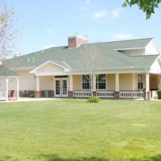 A single-story house with a green roof and spacious lawn.