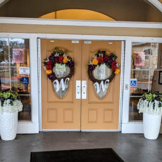 Decorated entrance with floral wreaths and potted plants.