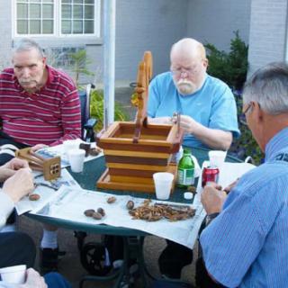 A group of seniors engaged in an outdoor activity around a table.