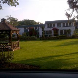 A charming house with a large lawn and a wooden gazebo.