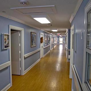 A hospital corridor with blue walls and a wooden floor.