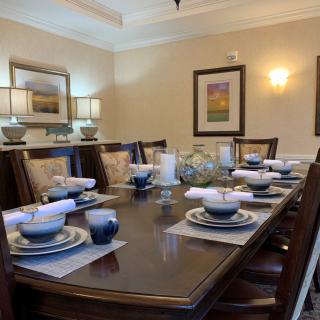 An elegantly set dining table in a well-decorated room with artwork on the walls.