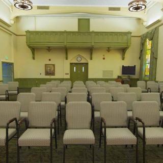 An empty meeting room with rows of chairs facing the front.