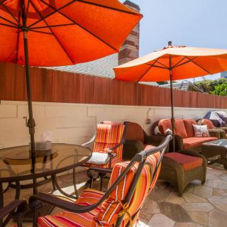 A cozy patio area with orange umbrellas, cushioned chairs, and a table set for outdoor relaxation.