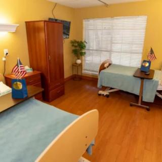 A hospital room with two beds, wooden floor, and flags on bedside tables.