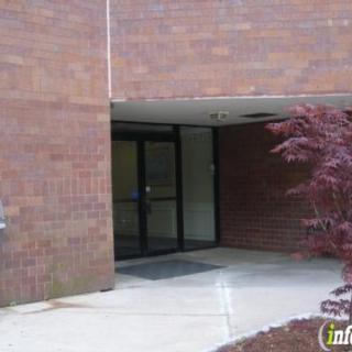 An exterior view of a building entrance with a glass door, surrounded by brick walls and landscaping.