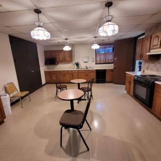 A kitchen interior featuring tables, chairs, and wooden cabinetry with overhead lighting.