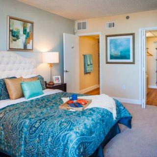 A cozy bedroom with stylish decor, including a bed with blue bedding and artwork on the walls.