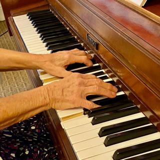 Hands playing a piano.