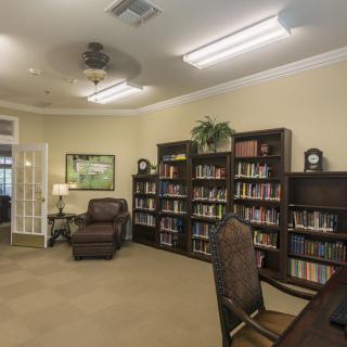 A cozy library room with bookshelves, an armchair, and a desk for reading.